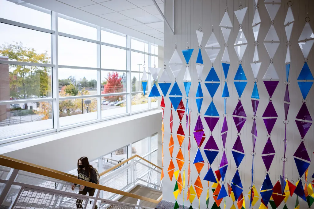 Student walking up stairs in University Center next to art installation.